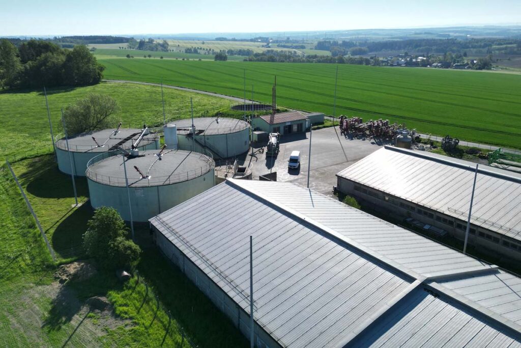 Ein Luftbild der Biogasanlage, sowie von 2 Hallen Auf dem Betriebsgelände sind Fahrzeuge und verschiedene Geräte zur Bodenbearbeitung zu sehen