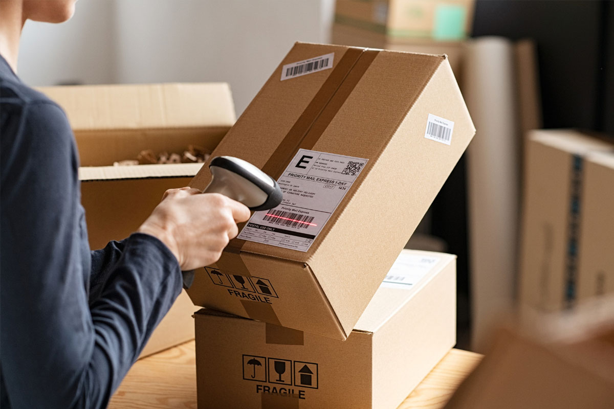 Eine Person scannt den Paketschein an einem Paket