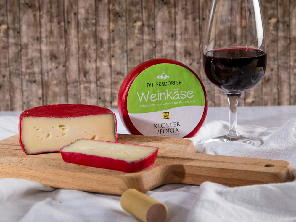 Ein aufgeschnittener Weinkäse und ein Glas Rotwein auf einem gedeckten Tisch