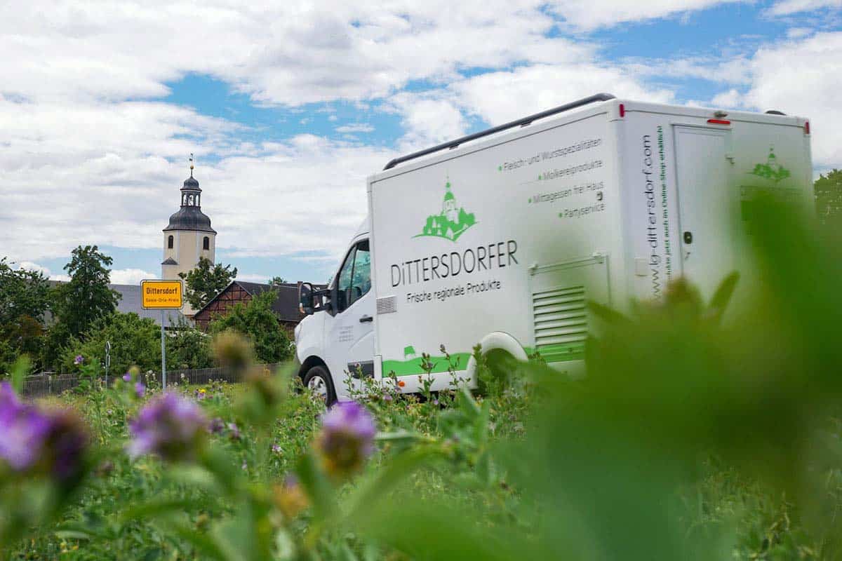 Unser Verkaufswagen am Ortseingang von Dittersdorf Im Hintergrund ist das Ortsschild sowie die Kirche zu sehen